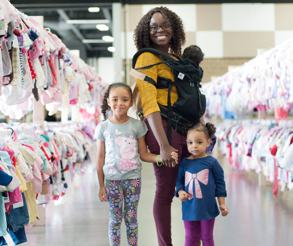A mom and her two kids stand in the shoe section for a happy family photo.
